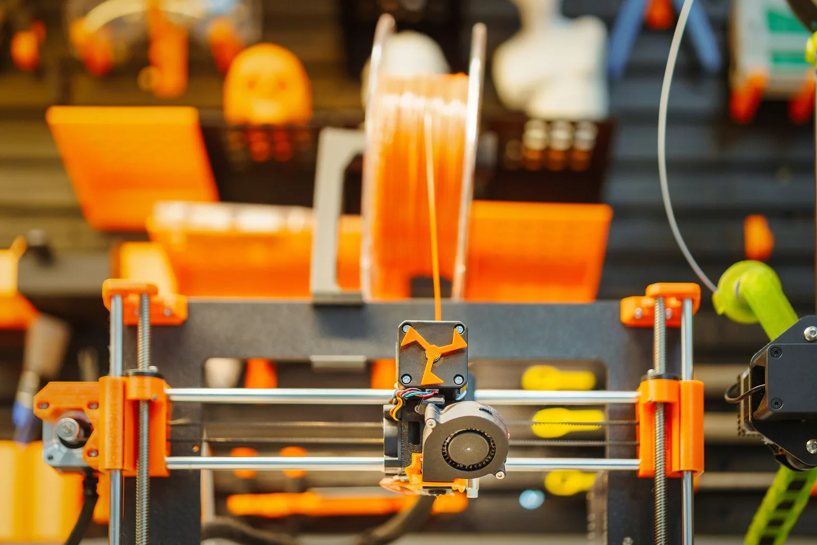 Imprimante 3D FDM en train d'extruder du filament orange, la première couche déposée sur le plateau à partir du G-code